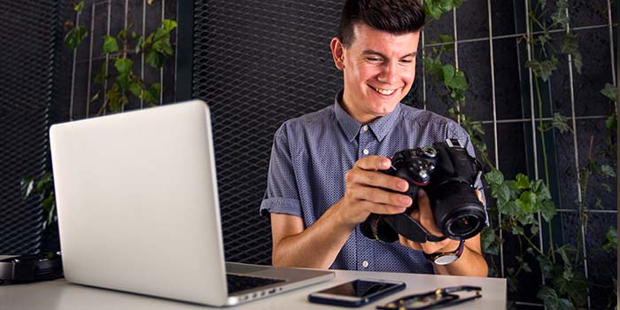 Young man recording a personalized video marketing message on a dslr camera - 700x350px